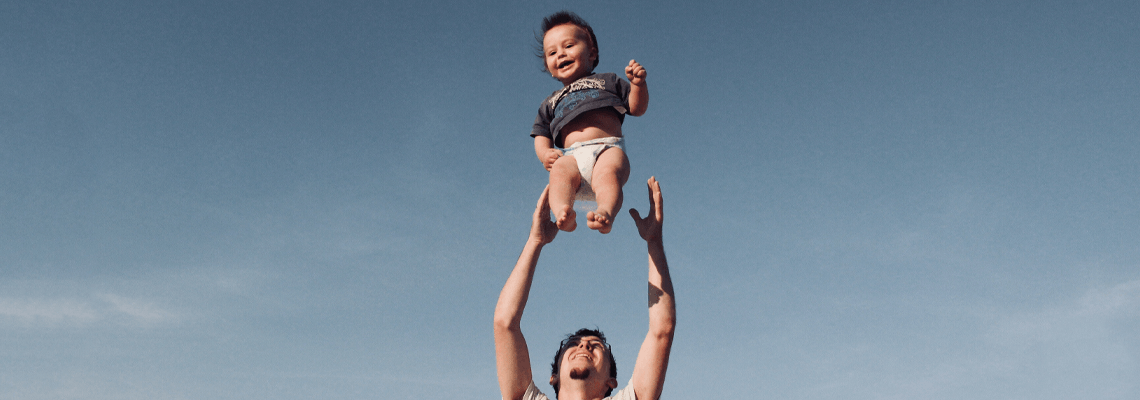 Father throwing and catching smiling baby in the air